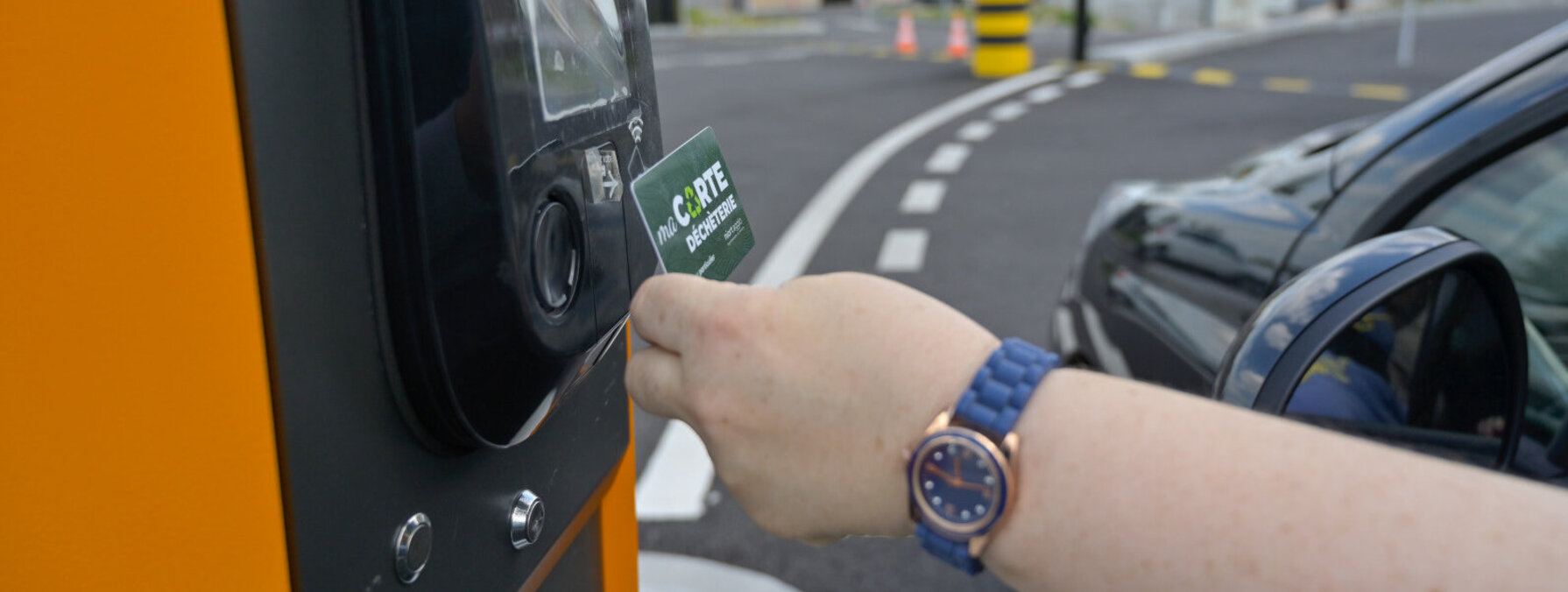 Main d'un usager présentant sa carte déchèterie à la borne d'accès depuis un véhicule