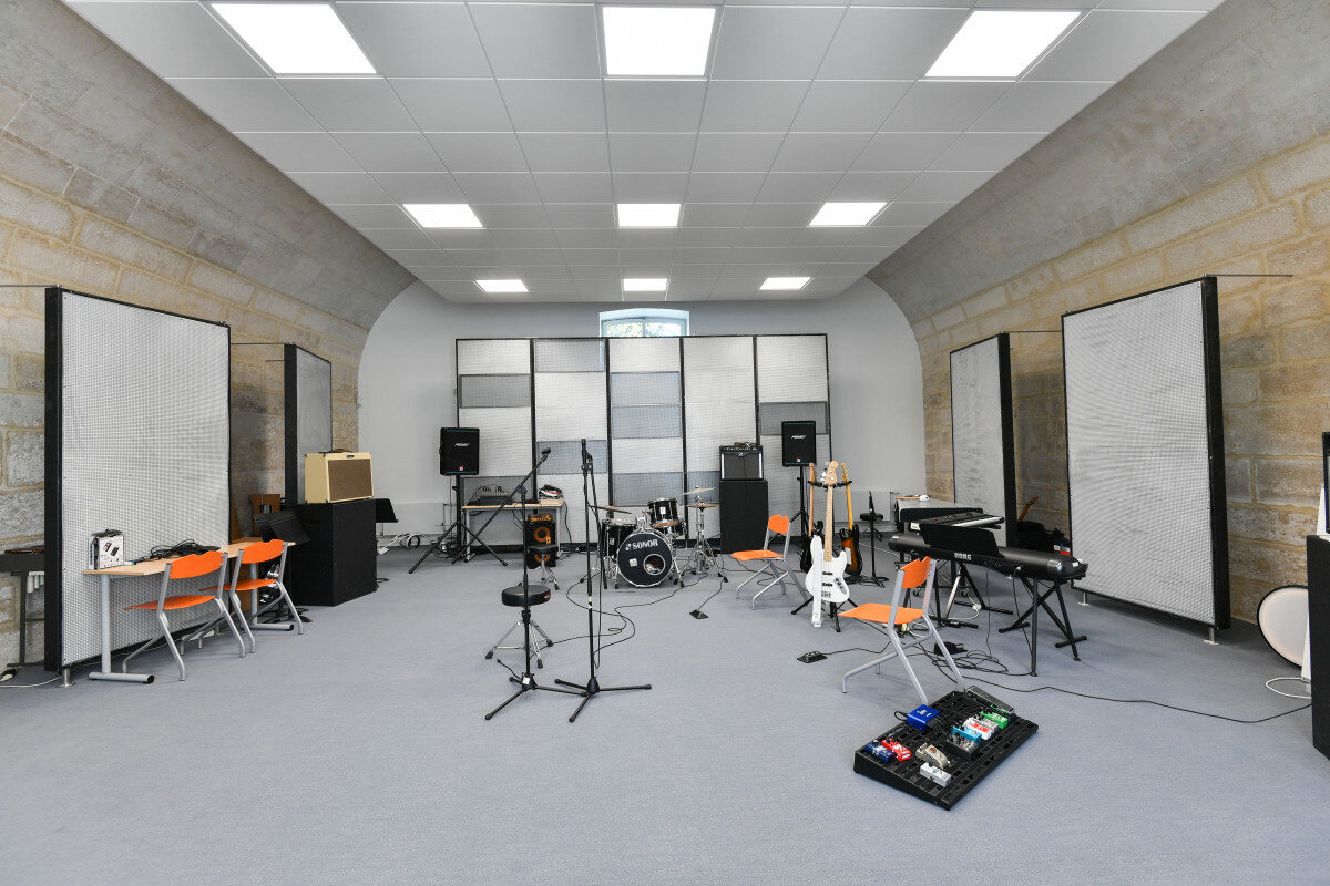 Salle de répétition du Conservatoire équipée d'une batterie, guitares électriques, amplificateurs et claviers