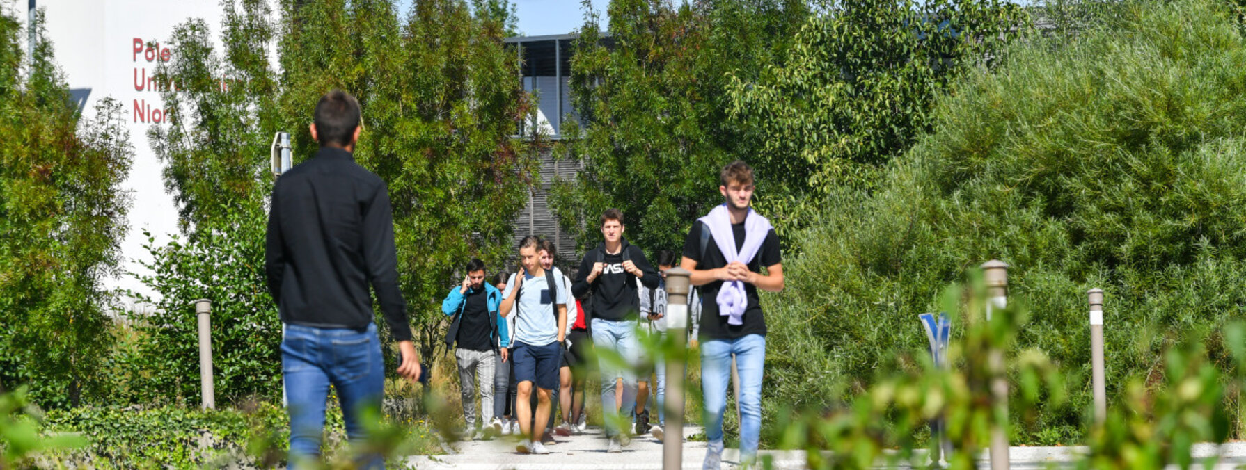 Étudiants marchant sur l'allée du Pôle Universitaire Niortais, bâtiment de l'Université de Poitiers visible en arrière-plan