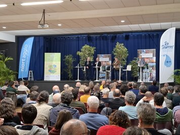 Quatre intervenants sur scène devant un large public réuni en salle pour une conférence de Niort Agglo