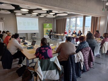 Salle de réunion avec une vingtaine de participants munis d'ordinateurs face à un écran de projection et une bannière Projet Alimentaire Territorial.