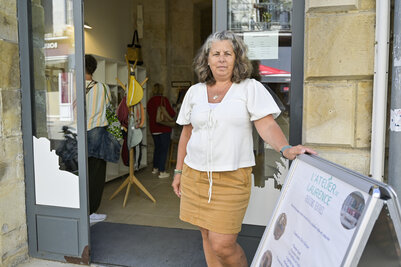 Une artisane posant à l'entrée de la boutique éphémère, à côté du panneau de L'Atelier de Laurence
