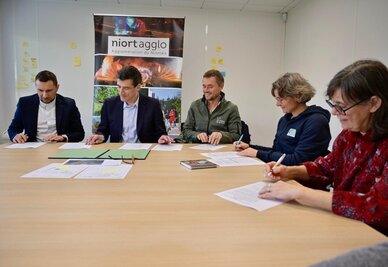 Jérôme Baloge, Président de Niort Agglo, et des partenaires signant une convention pour la plantation d'arbres, en salle de réunion.