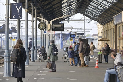 Quai de la gare de Niort avec des voyageurs dont une personne en fauteuil roulant, sous la marquise