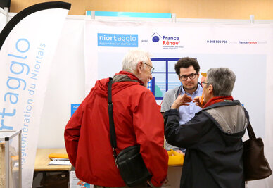 Stand Niort Agglo / France Rénov' lors d'un salon : un conseiller renseigne deux visiteurs sur leurs projets de rénovation