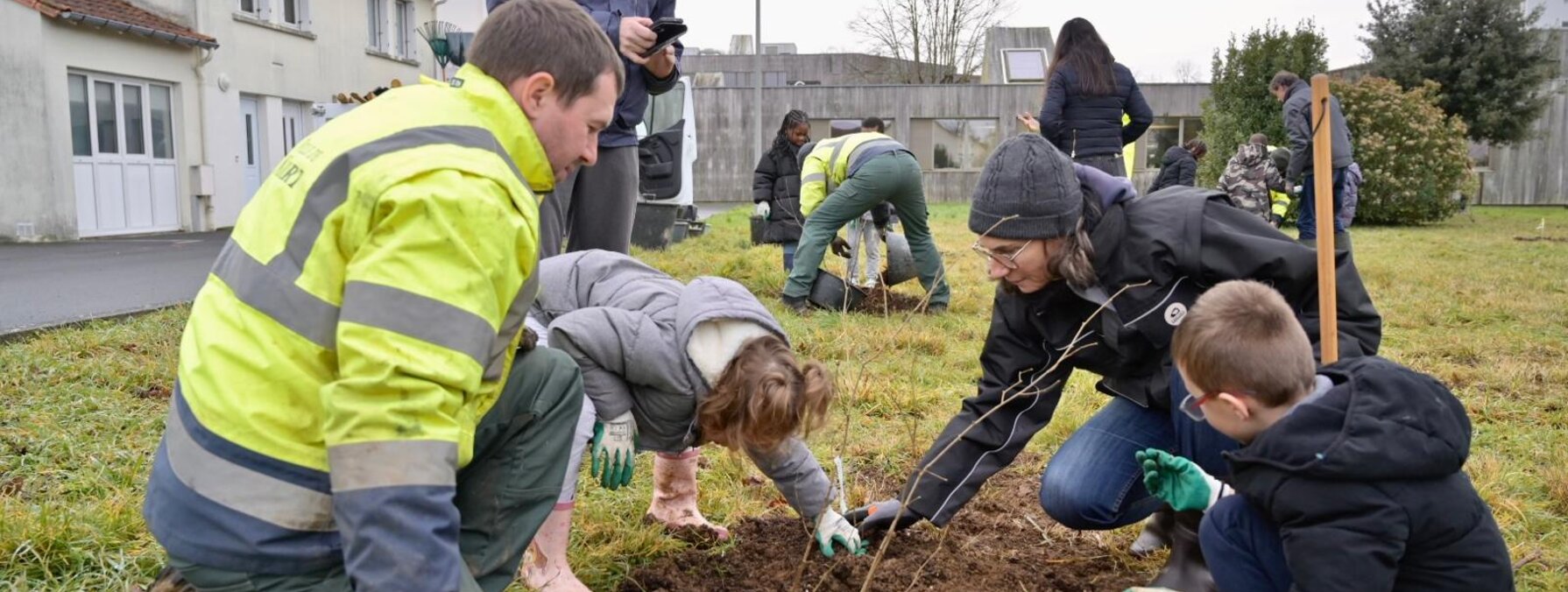 Agents municipaux et participants, dont des enfants, plantant des végétaux en pleine terre lors du chantier participatif du pollinarium.