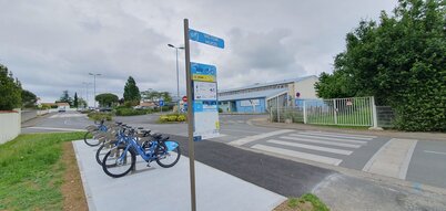 Trois vélos bleus du service VLS stationnés à la borne Victor Hugo de Bessines, face à un établissement scolaire