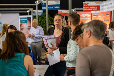 Participants en discussion avec des recruteurs devant les stands d'employeurs et de centres de formation