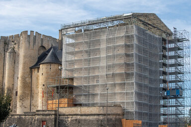 Tour nord du Donjon entièrement habillée d'un échafaudage métallique et de filets blancs,