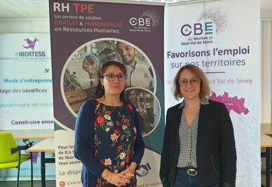 Deux femmes devant les roll-ups RH TPE et « Favorisons l'emploi sur nos territoires »