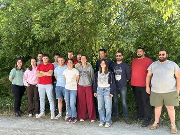 Groupe d'environ quinze participants au projet, posant ensemble en extérieur après la réunion bilan.