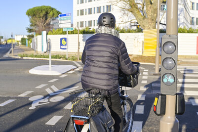 Un cycliste casqué à l'arrêt devant un feu cycliste dédié sur la piste aménagée de l'avenue de la Rochelle