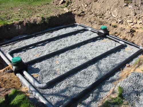 Installation d'assainissement non collectif avec réseau de tuyaux perforés posés dans une tranchée de graviers