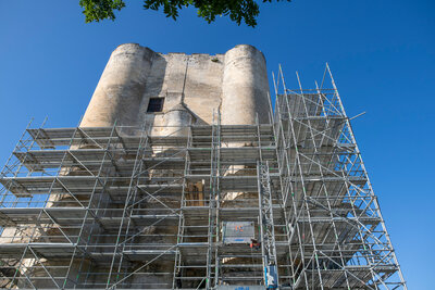 Tour nord du Donjon de Niort ceinte d'échafaudages métalliques en contre-plongée, fissures apparentes sur la façade de pierre