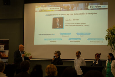 Conférence-table ronde Quartiers 2030 sur la création d'entreprise, avec participants et animateur devant un diaporama projeté